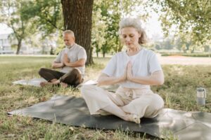 Seniors meditating to build mindfulness outside in a park