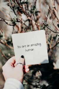 Person holding a square paper with the words "you are an amazing human"