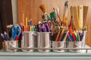 Art supplies - paint brushes, colored pencils, rulers, scissors in metal canisters