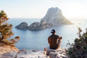 Man sitting on a rock overlooking the big rocks in the ocean