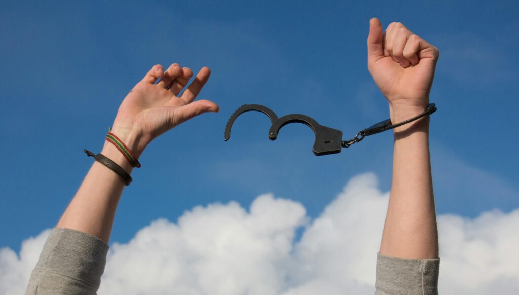 Hands in the air breaking free from handcuffs to symbolize using mindfulness to break free from pain